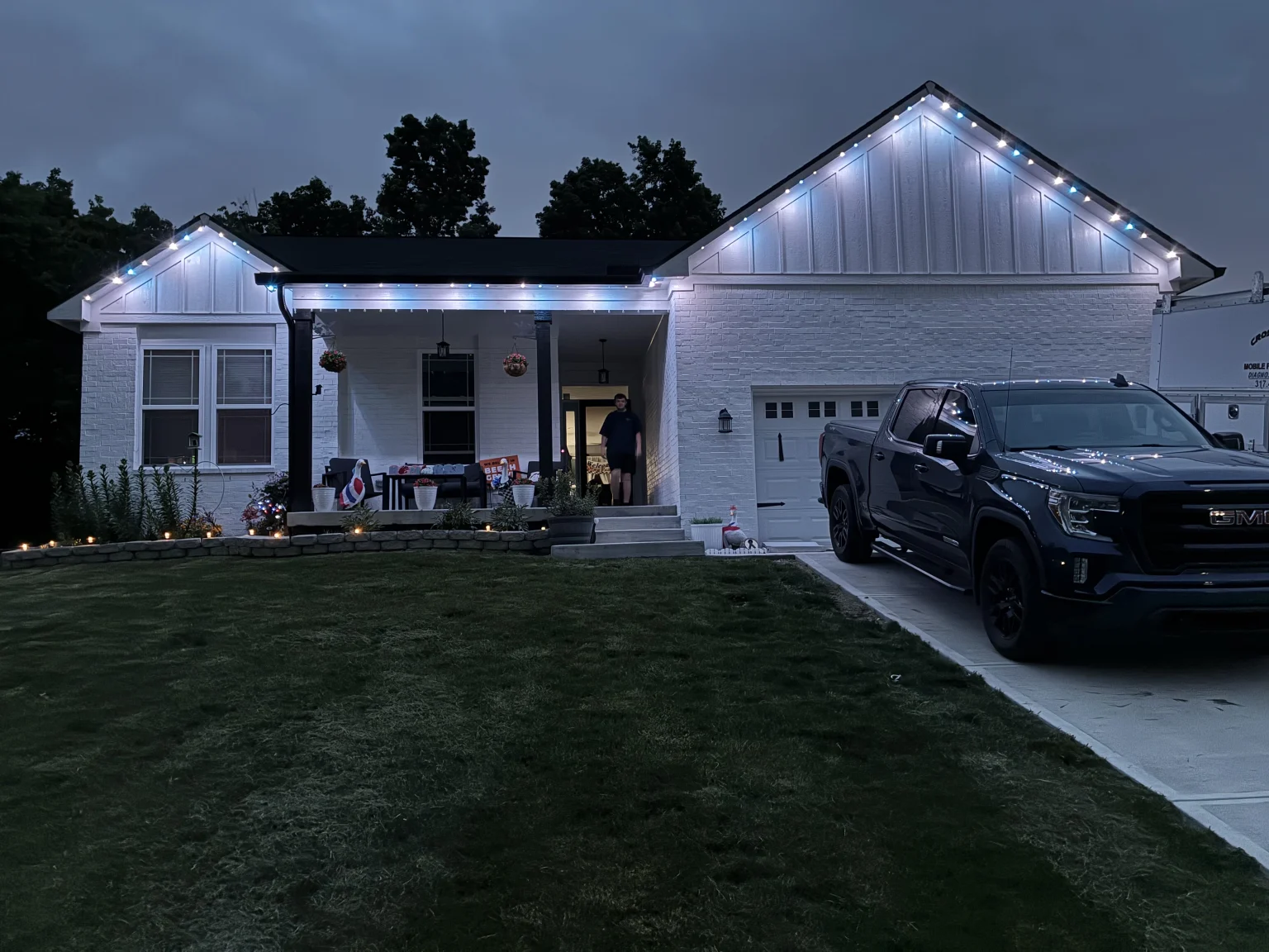 Home lit in icy winter holiday colors with permanent roofline lights